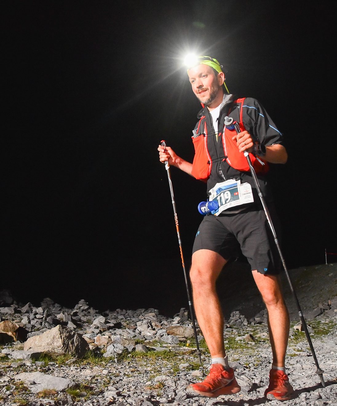 Yannik Bourquin en course de nuit, à la frontale, bâtons en main